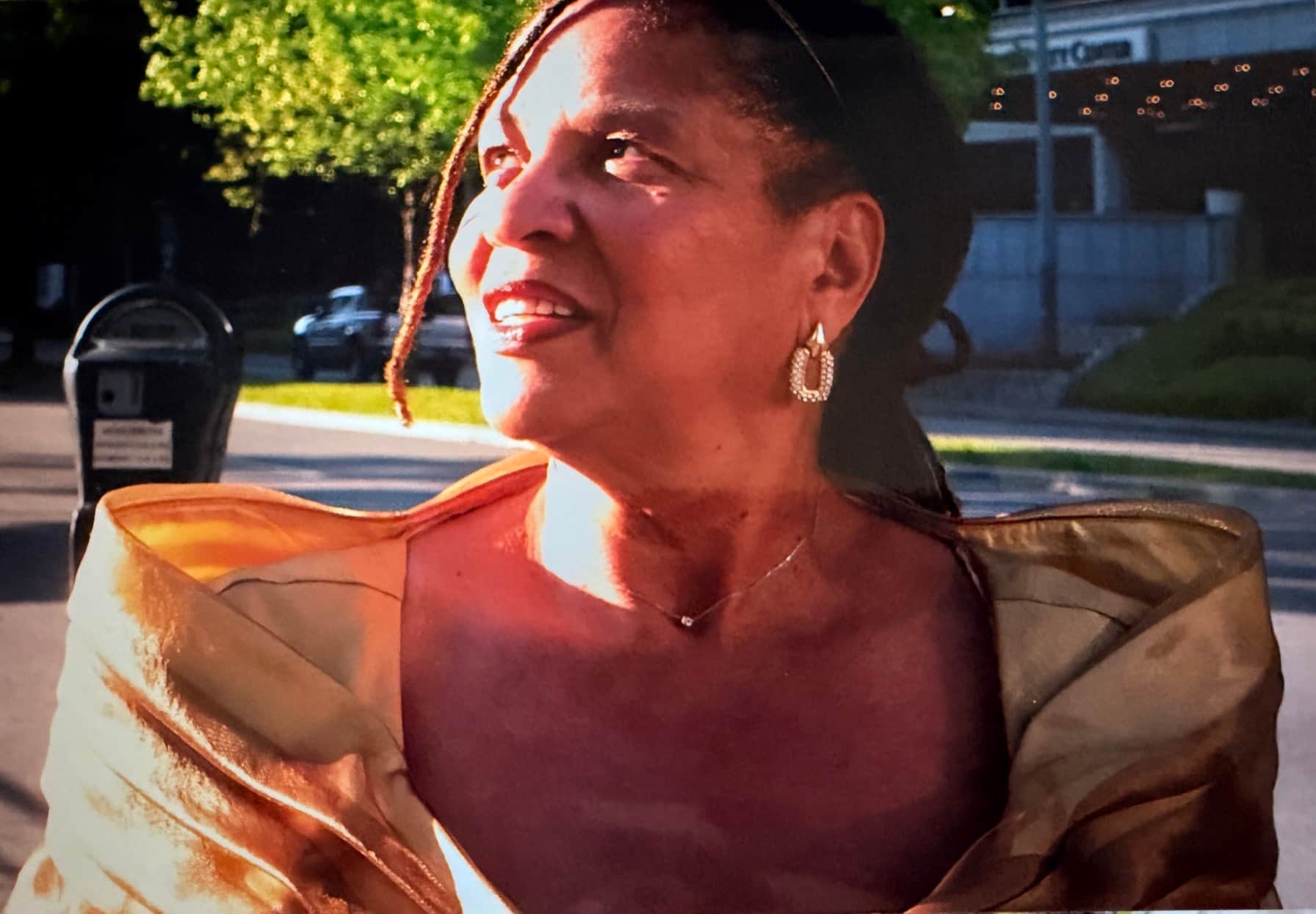Karen Blackwell smiling in golden-hour light, wearing a gold silk wrap