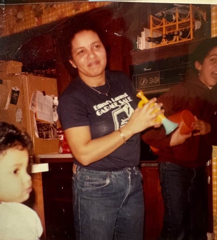 Karen laughing in the kitchen, toy horn in hand, kids at her side